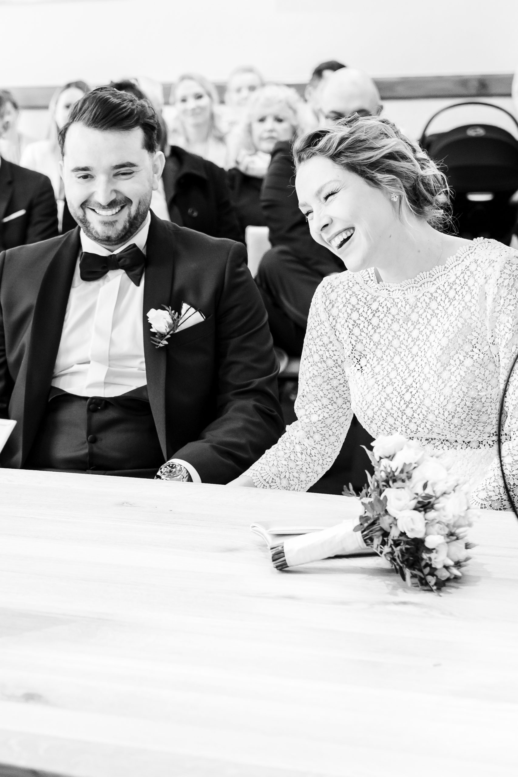 Ein schwarz-weiß Foto von einem lachendem Brautpaar während der Traurede im Standesamt im Rathaus Bergheim.