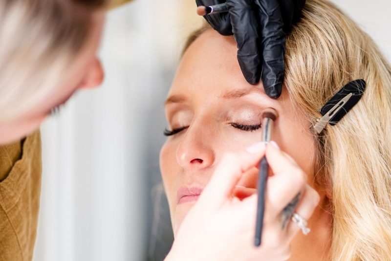 Eine Braut wird während des Getting Ready bei sich zuhause von einer Visagistin bzw. Stylisting oder Make-Up Artist für ihren Hochzeitstag geschminkt.
